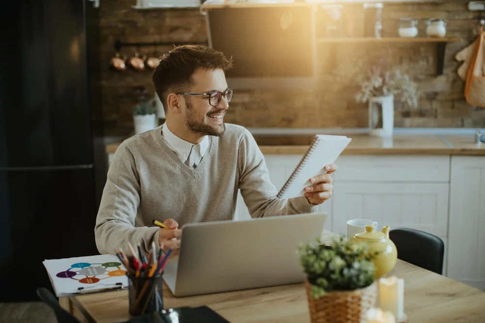 happy-entrepreneur-reading-notes-while-working-laptop-home.jpg